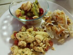 Low Cholesterol Egg and Tomato Scramble plated with hash browns and Fruit Salad with Honey Orange Dressing