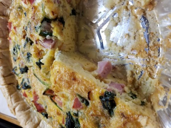 Spinach and Ham Quiche with slice out of pie plate so you can see the filling