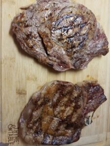 Grilled Cowboy Cut Ribeyes cooked and resting on cutting board