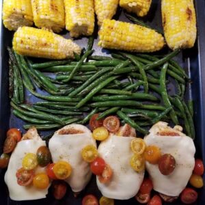 Baked Caprese Chicken with Green Beans And Corn on baking sheet just out of the oven.