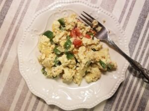 Garden Scrambled eggs on white plate with a fork.