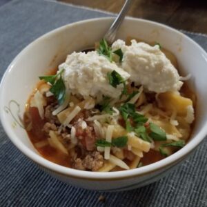 Cheesy Lasagna Soup with Ricotta Cheese garnish served in a white bowl.